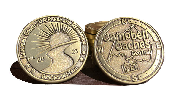 2 Gold coins are stood with different sides showing. One side has parks logo, the other Campbell Caches logo