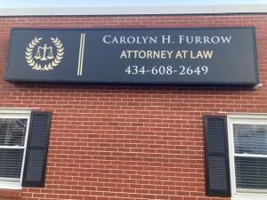 New Sign reads Carolyn H. Furrow Attorney at Law with phone number. Sign is on a brick building 