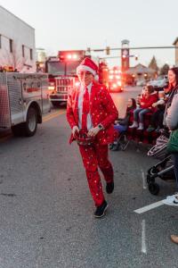 Santa clad fellow runs along parade route
