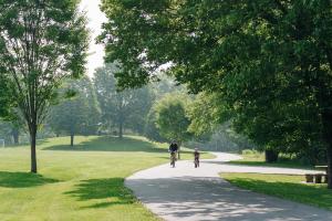 Father and son bike along paved trails in park