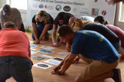 Local sponsors kneel to outline their hands and sign the floor of the Dream Home