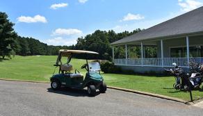 Golf cart is parked outside the clubhouse with wraparound deck