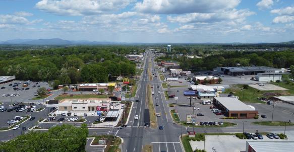 Aerial view of busy Timberlake Road with businesses on both sides and green space in distance