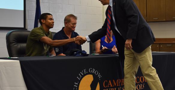 Principal Hardie shakes hands with graduate on CTE Signing Day