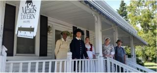 Colonial Reenactors Stand on the Porch with a sign reading "Mead's Tavern"