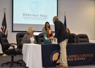 Principal shakes hand of graduate signing with Heritage Hall