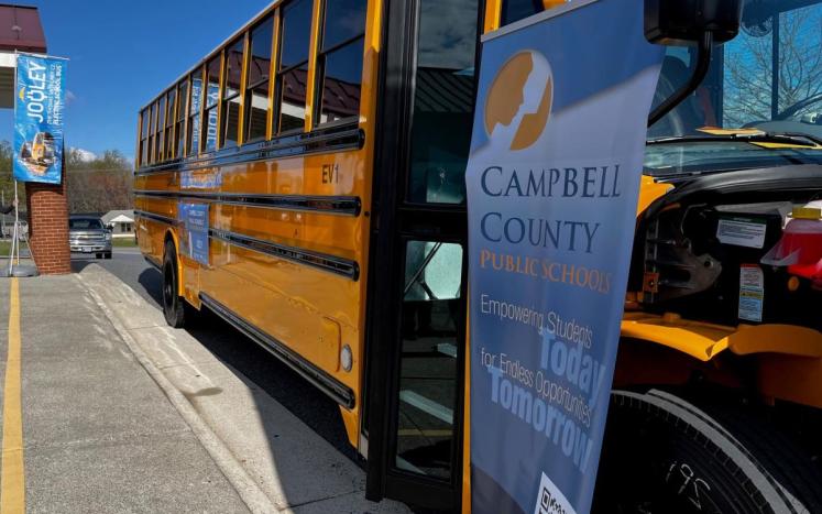 Campbell County's first electric bus parked along front of school