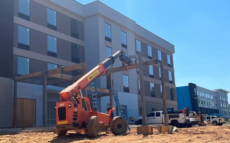 Construction crane lowers final beam onto entryway of new Home2Suites hotel in Campbell County